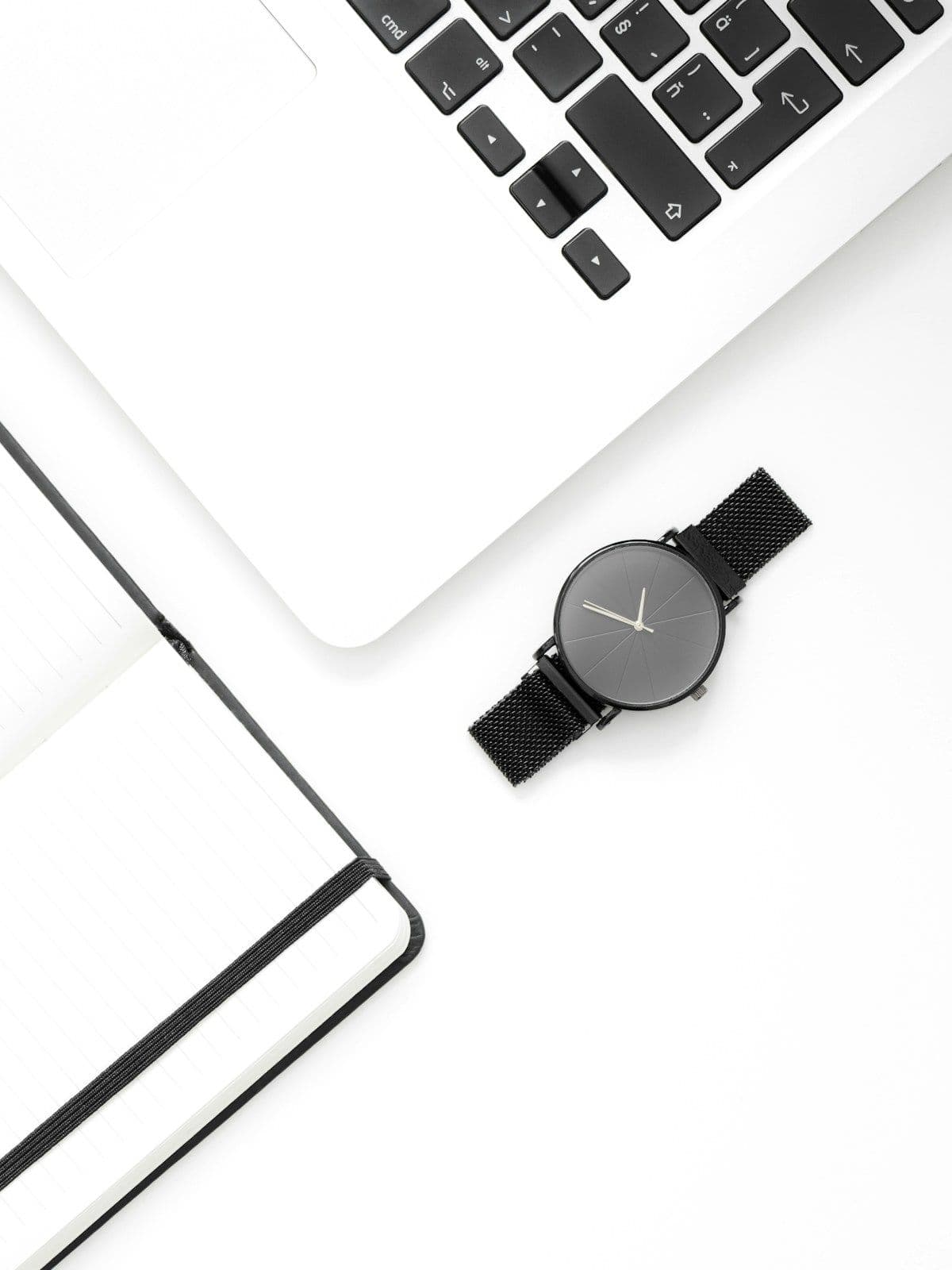 Laptop, notebook, and watch on a bright minimal desk